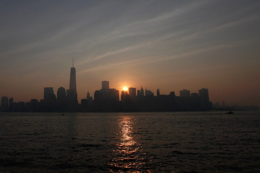 The sun rises behind New York’s Lower Manhattan and One World Trade Center as seen from Liberty State Park in Jersey City