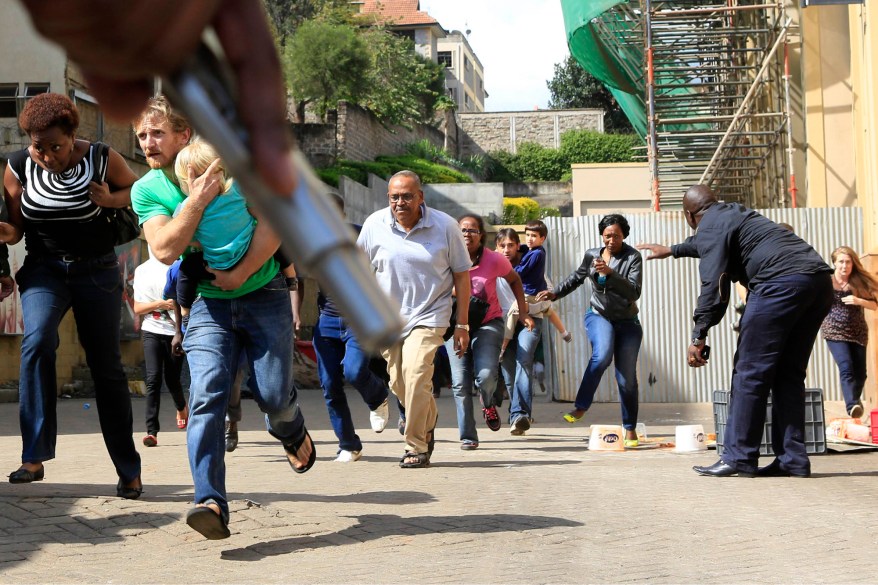 Police officer holds a gun to provide cover for customers running out as a shooting took place at Westgate shopping mall in Nairobi