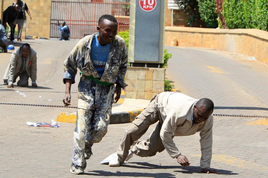 Construction workers run following a shootout between unidentified armed men and the police at the Westgate shopping mall in Nairobi