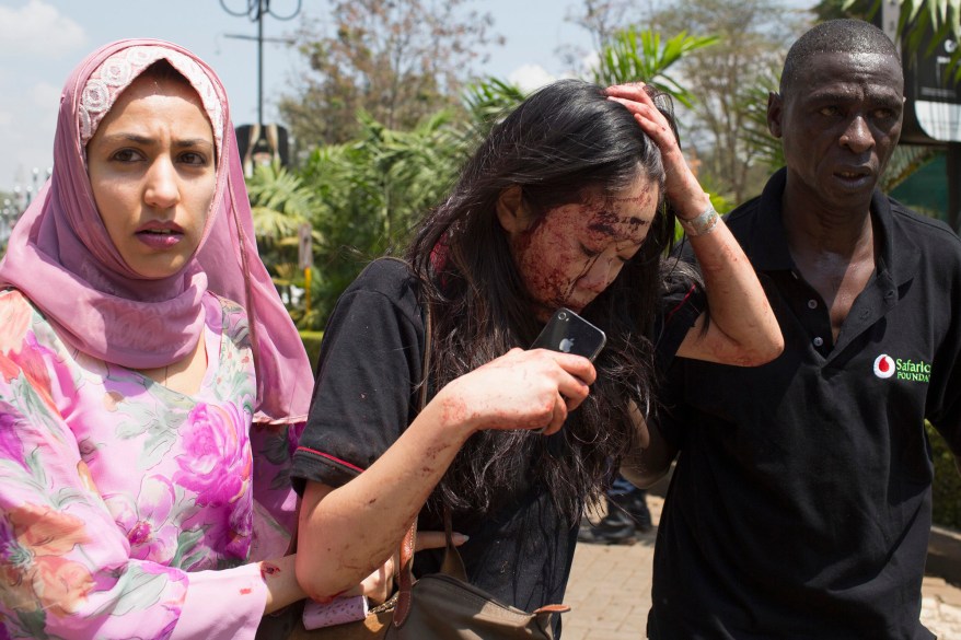 An injured woman is helped out of the Westgate Shopping Centre where gunmen went on a shooting spree, in Nairobi