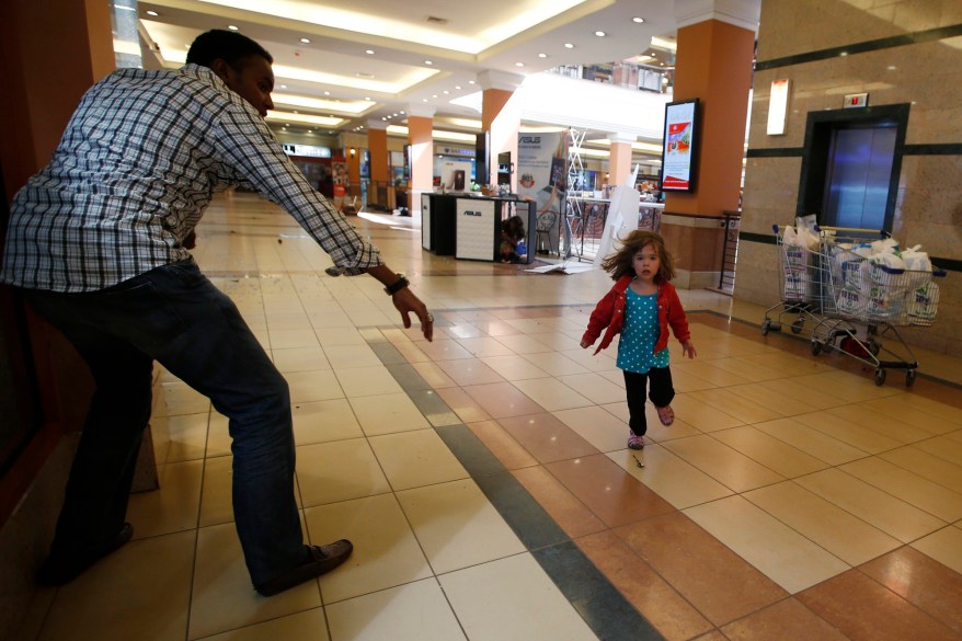 A child runs to safety as armed police hunt gunmen who went on a shooting spree at Westgate shopping centre in Nairobi