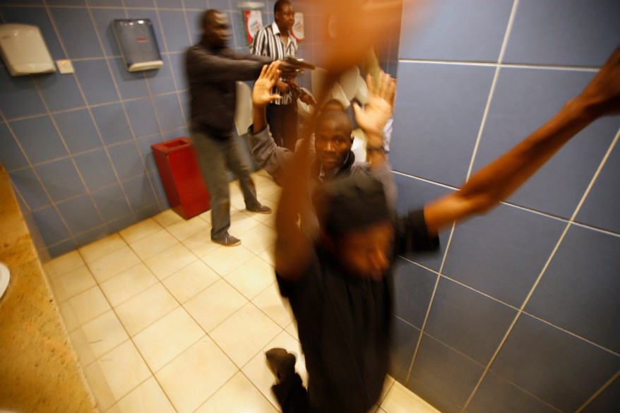 Armed police search customers inside a bathroom while combing through a shopping centre for gunmen in Nairobi