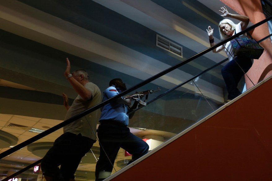 A police officer secures an area as civilians flee inside Westgate Shopping Centre in Nairobi