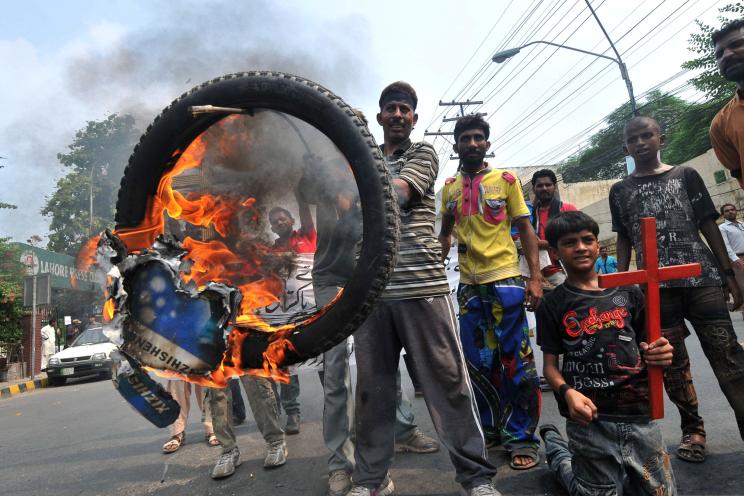 Pakistani Christians hold a burning tire as they stage a protest in Lahore Monday against the suicide bombing of a church in Peshawar.