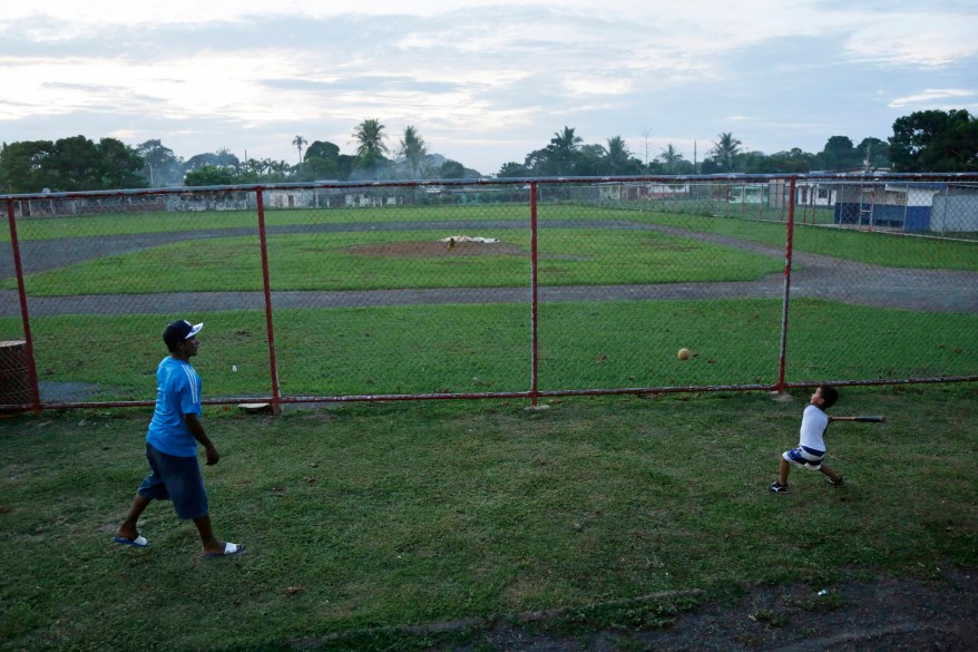 People play outside a fenced in baseball field where New York Yankee pitcher Mariano Rivera played during his childhood in Puerto Caimito, Panama. Rivera and his friends played their youthful baseball on the beach with tennis balls, or balls fashioned from fish nets. Bats were made from branches from the mangrove swamps, and gloves were empty milk cartons.