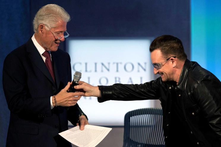 Bono bows to as he hands the mic over to President Clinton after speaking at Tuesday's Clinton Global Initiative event.