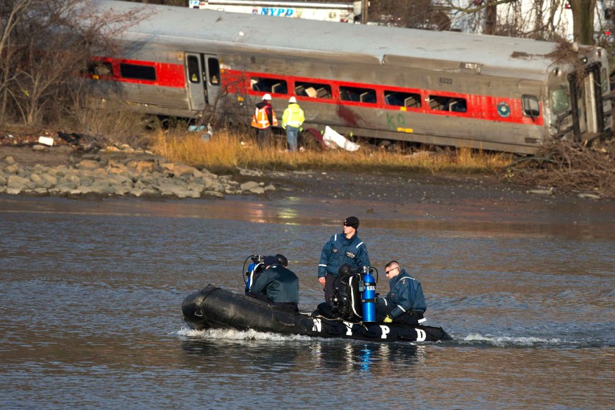 New York Police Department officials use a boat to search the waters around the site of a Metro-North train derailment in the Bronx borough of New York