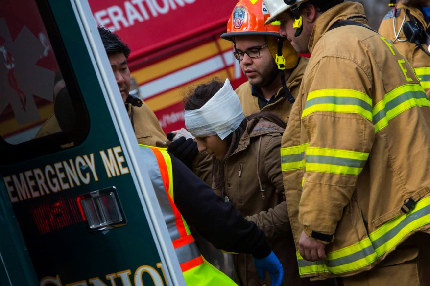 A woman is taken to an ambulance at the site of a Metro-North train derailment.