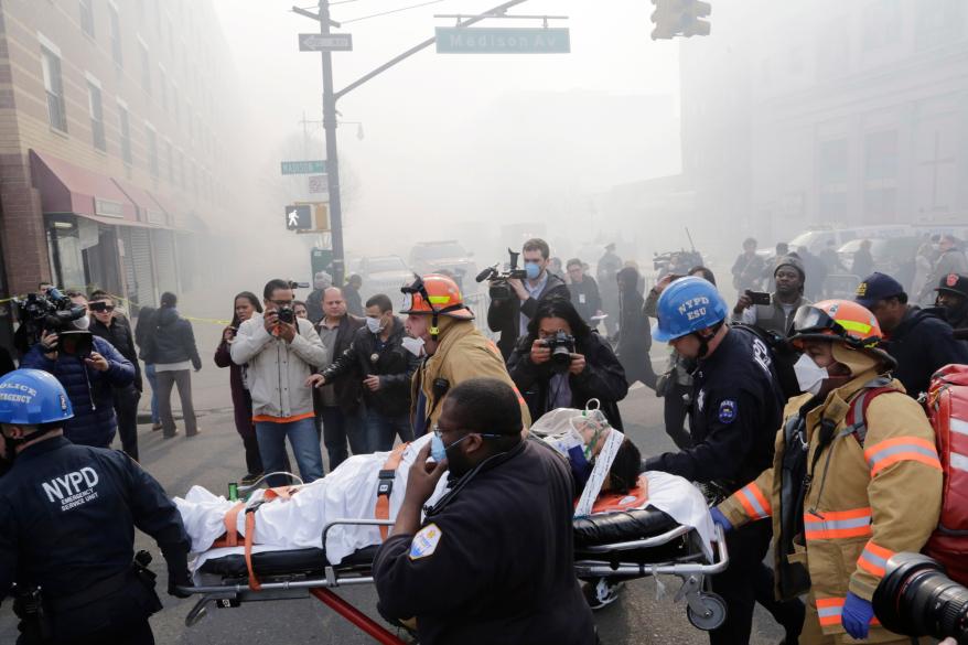 Rescue workers remove an injured person on a stretcher after an explosion and building collapse in East Harlem Wednesday.