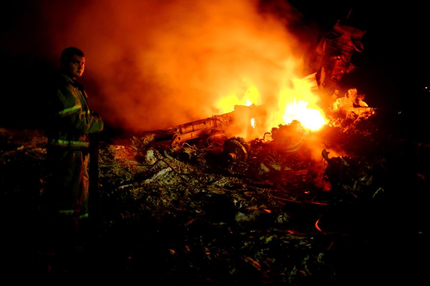 A firefighter works to put out a fire among the wreckage of Flight MH17