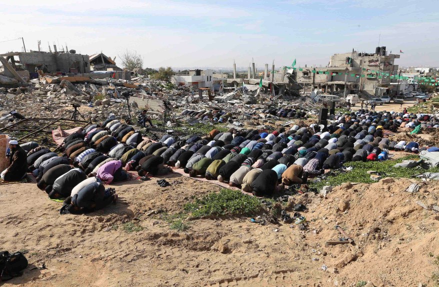 Palestinians perform Friday prayers near the ruins of houses that witnesses said were destroyed or damaged by Israeli shelling during a 50-day war last summer, in the village of Johar a-Deek near the central Gaza Strip January 23, 2015. REUTERS/Ibraheem Abu Mustafa (GAZA - Tags: POLITICS RELIGION CIVIL UNREST TPX IMAGES OF THE DAY)