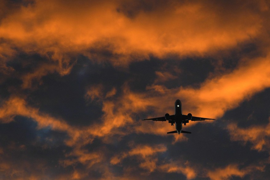 A passenger plane flies towards Heathrow airport at dawn in London.