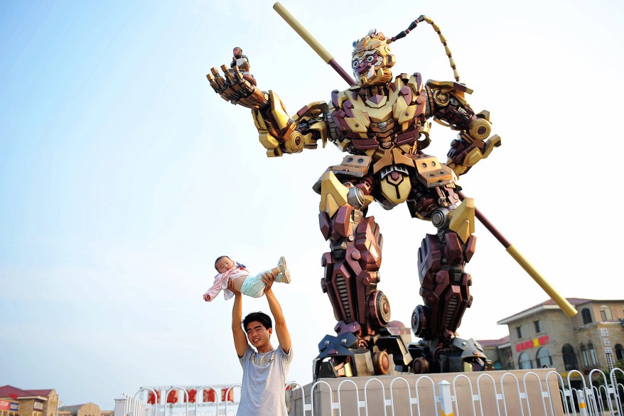 A visitor shows off his baby in front of a statue of the Monkey King in Qingdao, China.