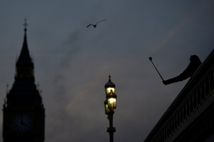 A person takes a photograph on Westminster Bridge at dusk in central London.