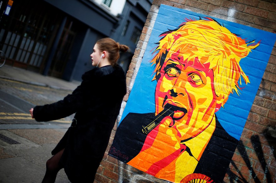 A woman walks past a caricature of Britain's Foreign Secretary Boris Johnson in east London.