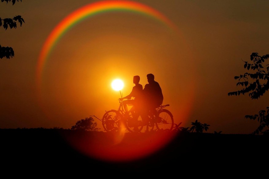 Boys are silhouetted against the setting sun as they ride bicycles on the outskirts of Agartala, India.