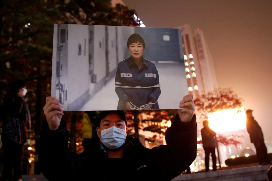 A protester holds a computerized image of South Korean President Park Geun-hye, at a candlelight protest demanding President Park step down over a recent influence-peddling scandal, in central Seoul, South Korea.