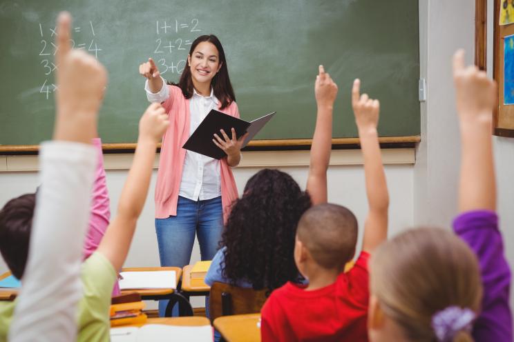 Teacher calling on children raising their hands.