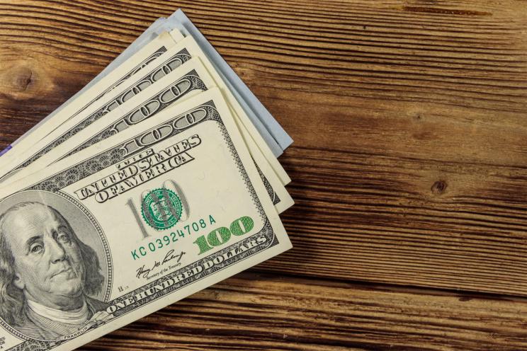 Stack of one hundred dollars bills on wooden desk