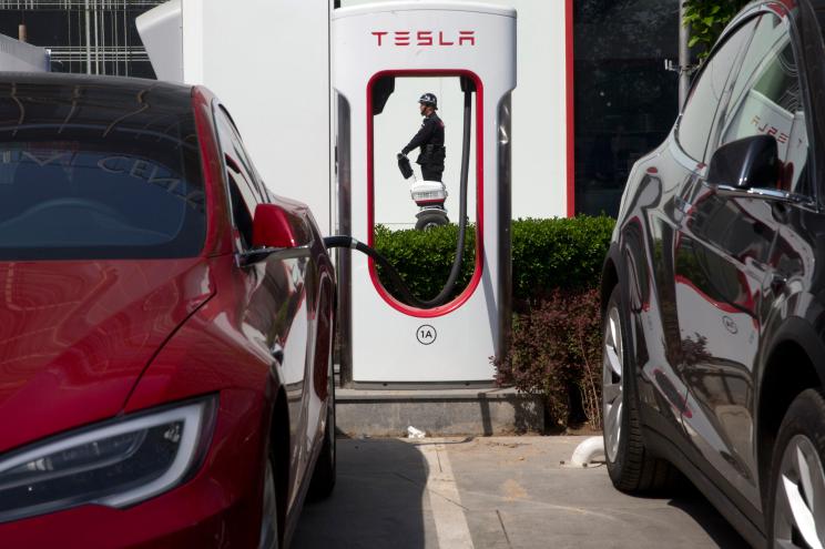 A security guard moves past Tesla electric vehicle charging station in Beijing.