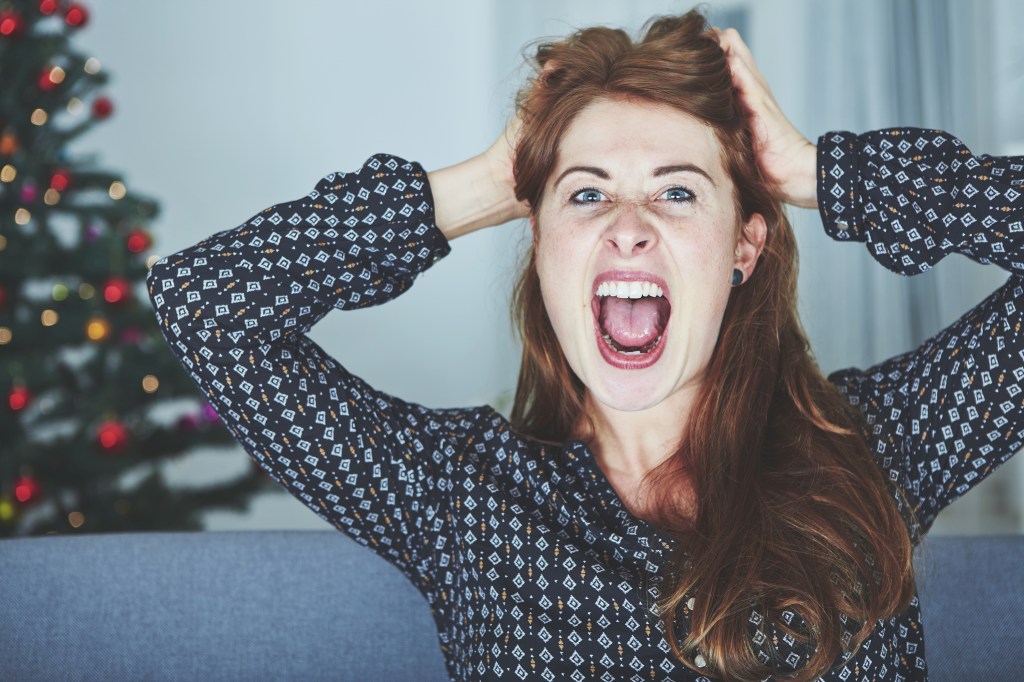 Woman yelling on the couch by a Christmas tree.