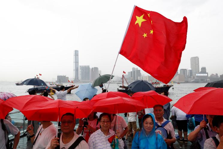 Pro-China supporters hold red umbrellas and a Chinese national flag during a counter-rally in support of the police in Hong Kong.