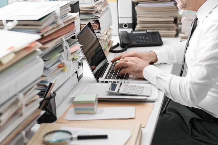 An employee works in an office at their desk with a computer