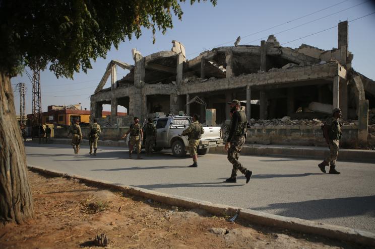 Turkish-backed Syrian fighters walk down a street in the border Syrian town of Tal Abyad