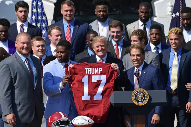 President Donald Trump holds up a jersey with the 2017 Alabama football team.