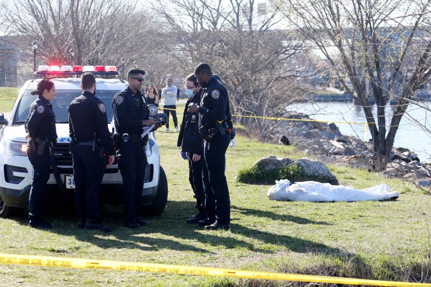 Police near the body that was discovered in a crowded Little Bay Park in Queens today.