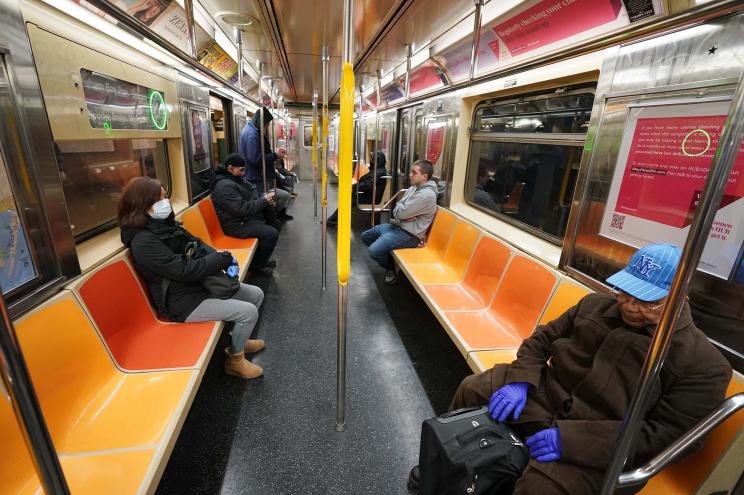 Downtown 6 train commuters seated far apart, some wearing mask and gloves due to coronavirus.