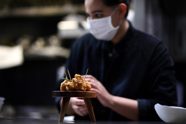 France's youngest Michelin-starred chef, Julia Sedefdjian, walking past the "Accra de morrue" as she prepares a dish for take-away sales on April 30, 2020.