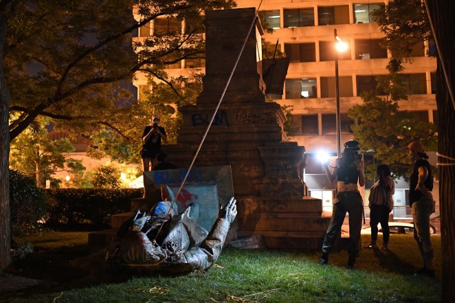 People stand around the statue of Confederate general Albert Pike after it was toppled by protesters at Judiciary square in Washington, DC.