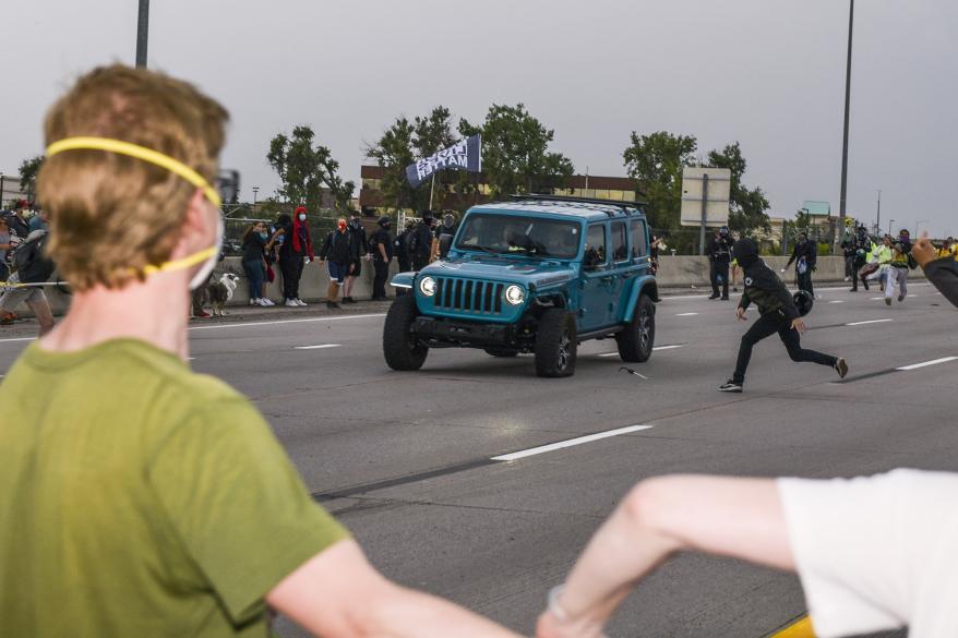 People run to get out of the way as a Jeep speeds through a crowd of people protesting the death of Elijah McClain on Interstate 225 in Aurora, Colorado.