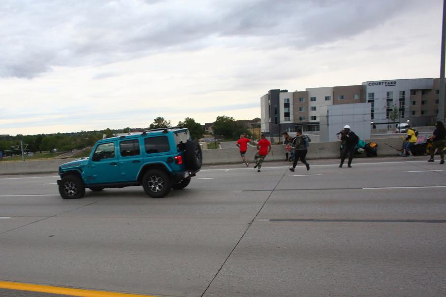 People run to get out of the way as a Jeep speeds through a crowd of people protesting the death of Elijah McClain on Interstate 225 in Aurora, Colorado.