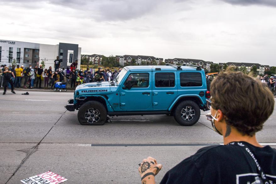 People run to get out of the way as a Jeep speeds through a crowd of people protesting the death of Elijah McClain on Interstate 225 in Aurora, Colorado.