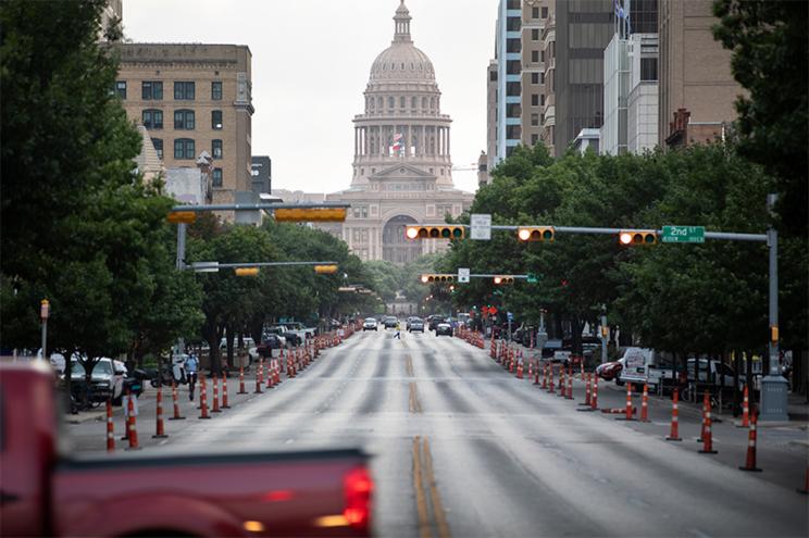 Cars drive on Congress Avenue in front of the Texas Capitol building