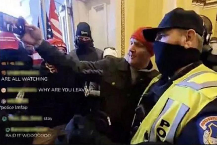 A still taken from a clip of a live broadcast made inside the U.S. Capitol after rioters breached police lines and stormed the building shows a Capitol police officer taking seflies with rioters