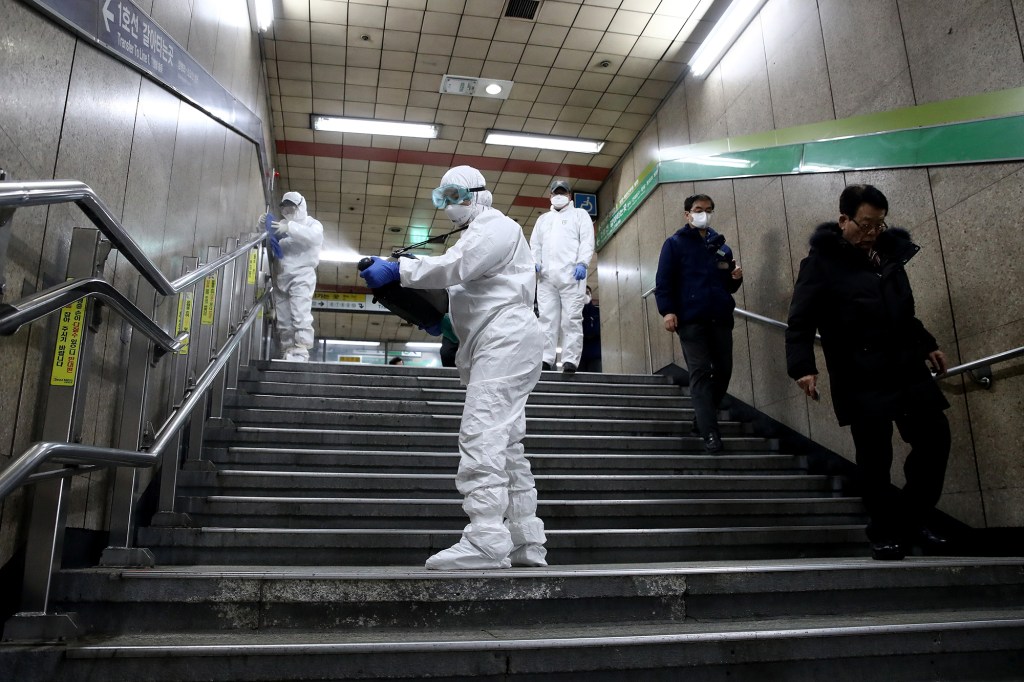 Disinfection workers wearing protective gears spray anti-septic solution against COVID-19 at a subway station in Seoul, South Korea