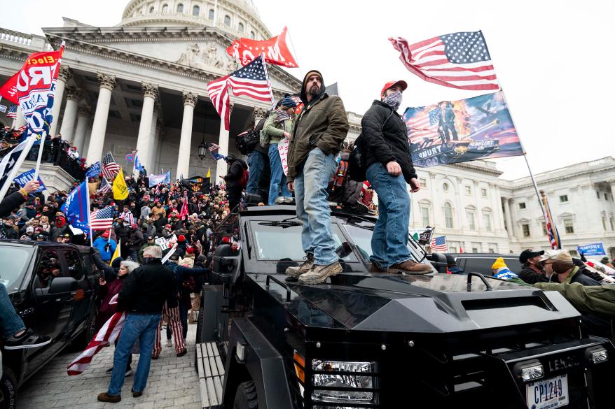 Trump supporters stand on a U.S. Capitol Police armored vehicle as others storm the steps of the Capitol.