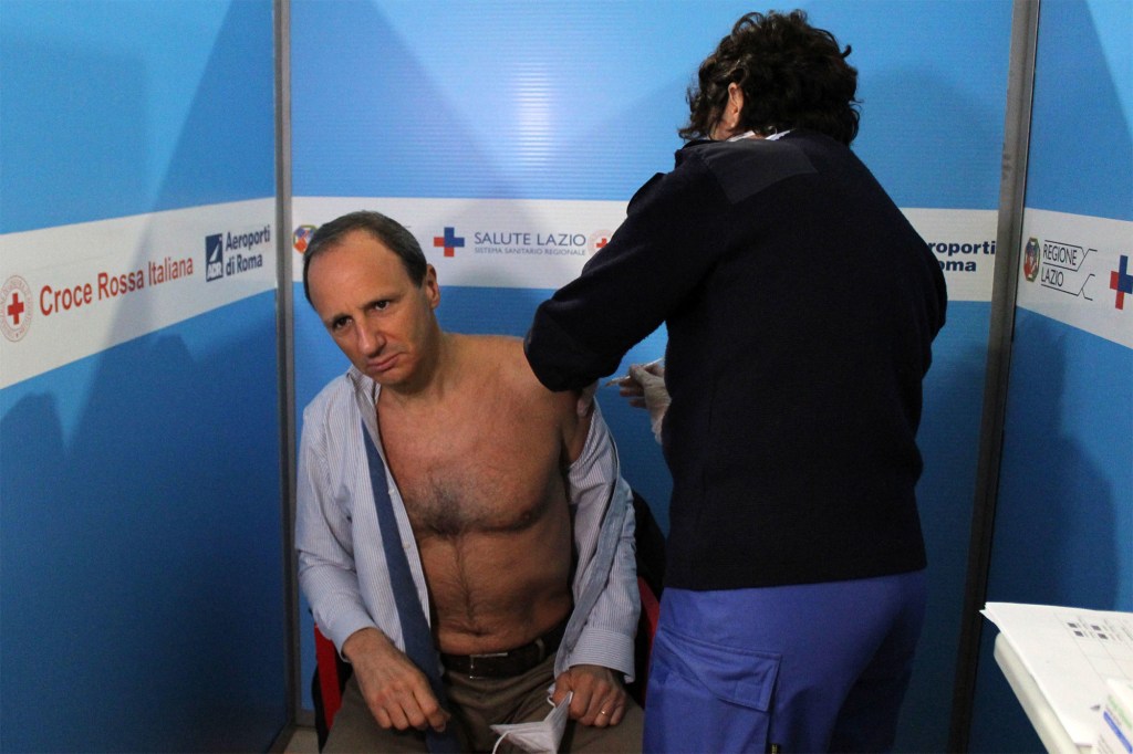 A nurse vaccinates 54-year-old ophthalmologist Marco Buglione with the Oxford-AstraZeneca coronavirus vaccine at Rome's Leonardo Da Vinci Fiumicino Airport in Italy.