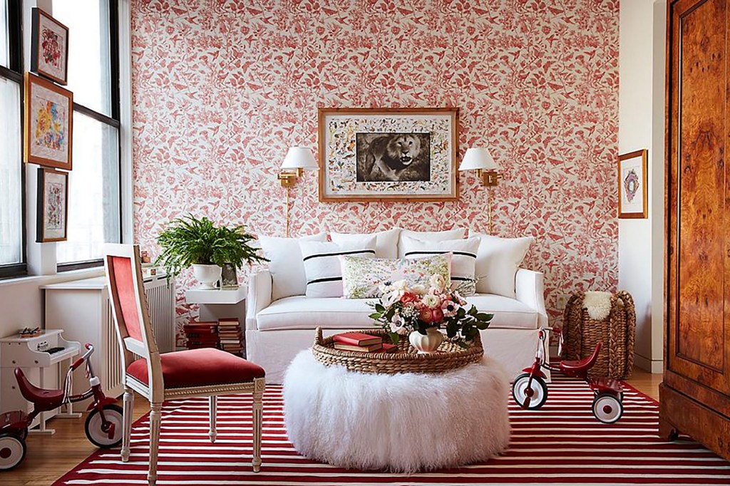 A pink and white children's playroom with white furniture and a red trike 