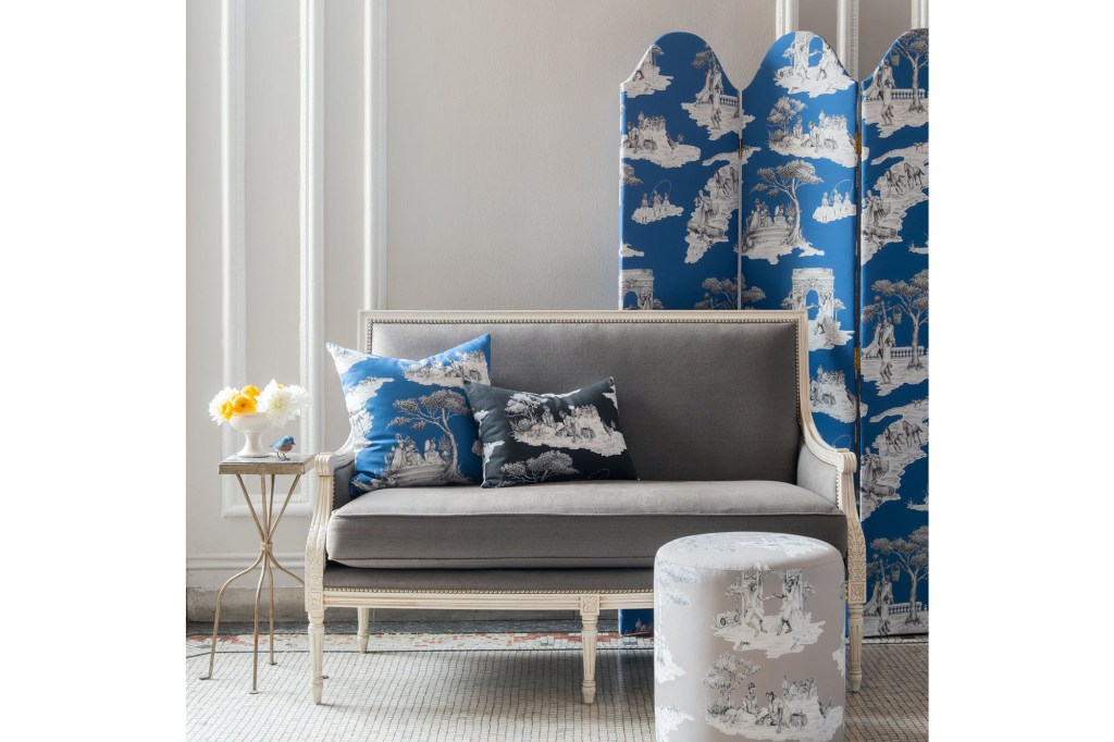 A grey sofa and a blue and white patterned room divider and matching pillows 