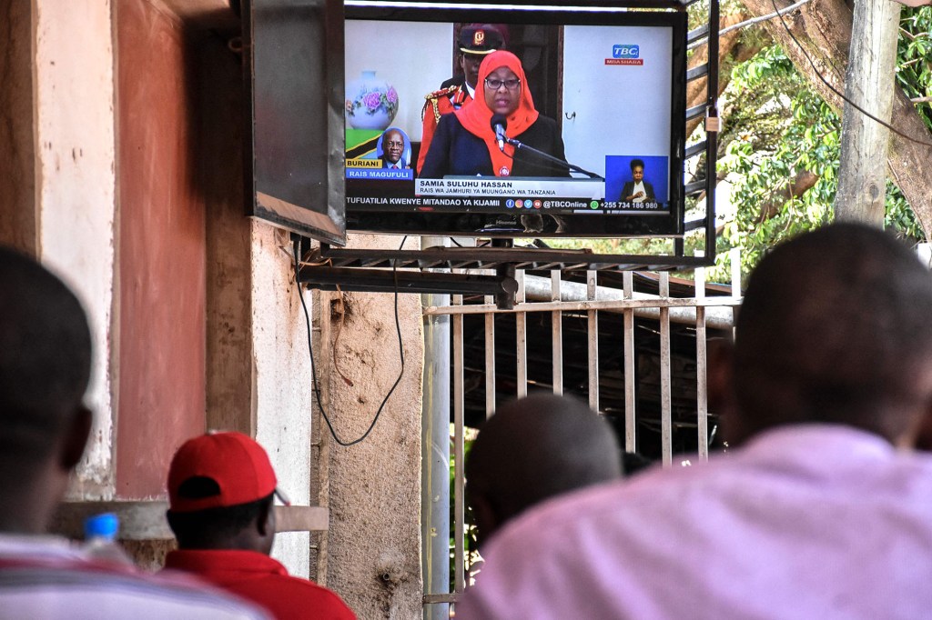 People watch TV showing new Tanzanian President Samia Suluhu Hassan after swearing-in ceremony.