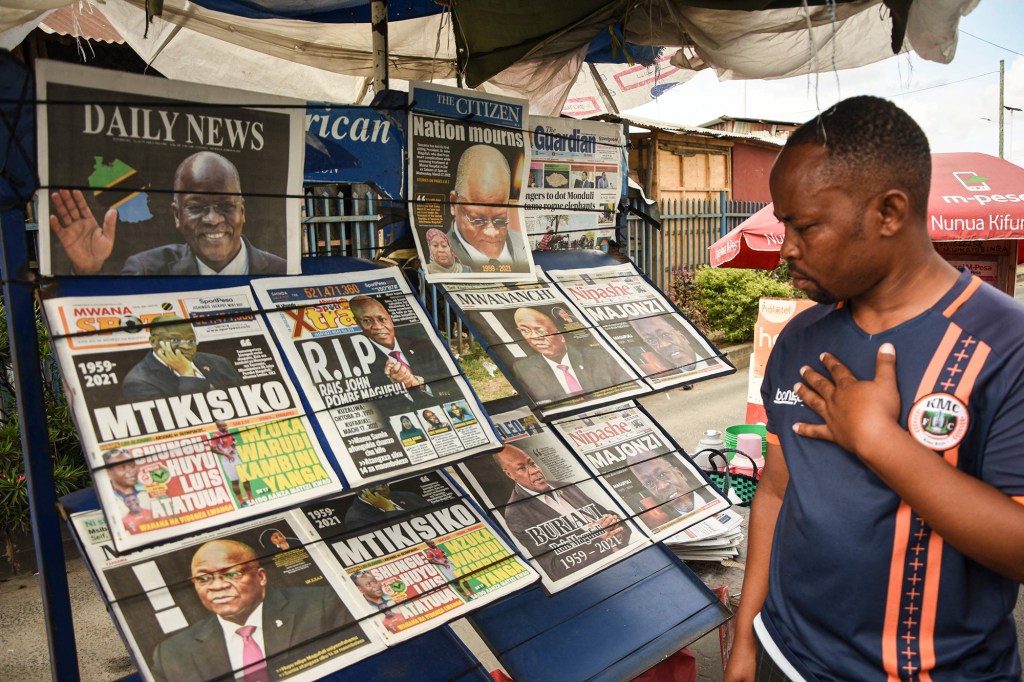 A man reacts as he sees newspapers with headlines announcing the death of Tanzania's President 