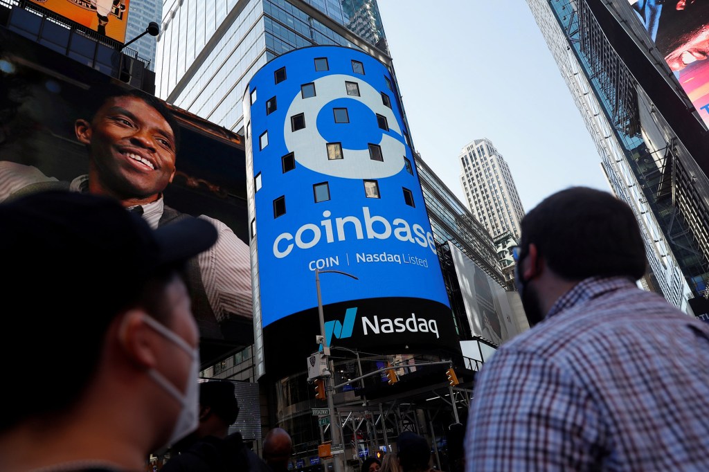 People watch as the logo for Coinbase Global Inc, the biggest U.S. cryptocurrency exchange, is displayed on the Nasdaq MarketSite jumbotron at Times Square