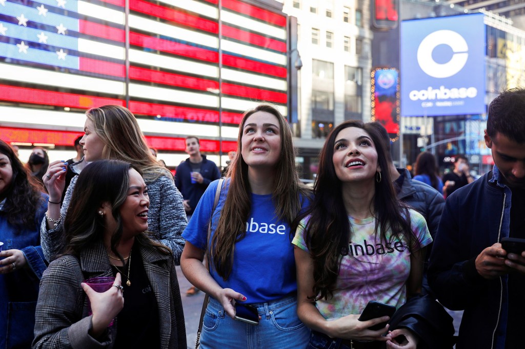 Employees of Coinbase Global Inc, the biggest U.S. cryptocurrency exchange, watch as their listing is displayed on the Nasdaq MarketSite jumbotron at Times Square in New York