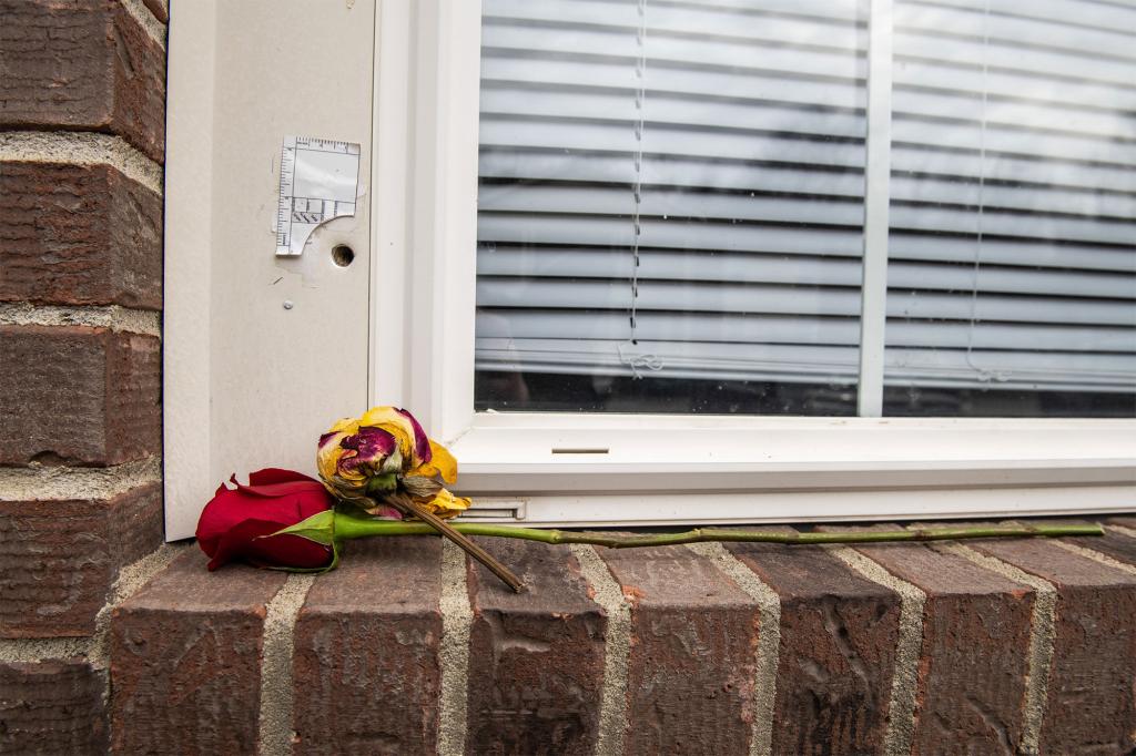 Two roses sit below a bullet hole on the window sill of Breonna Taylor's apartment where she was murdered by LMPD