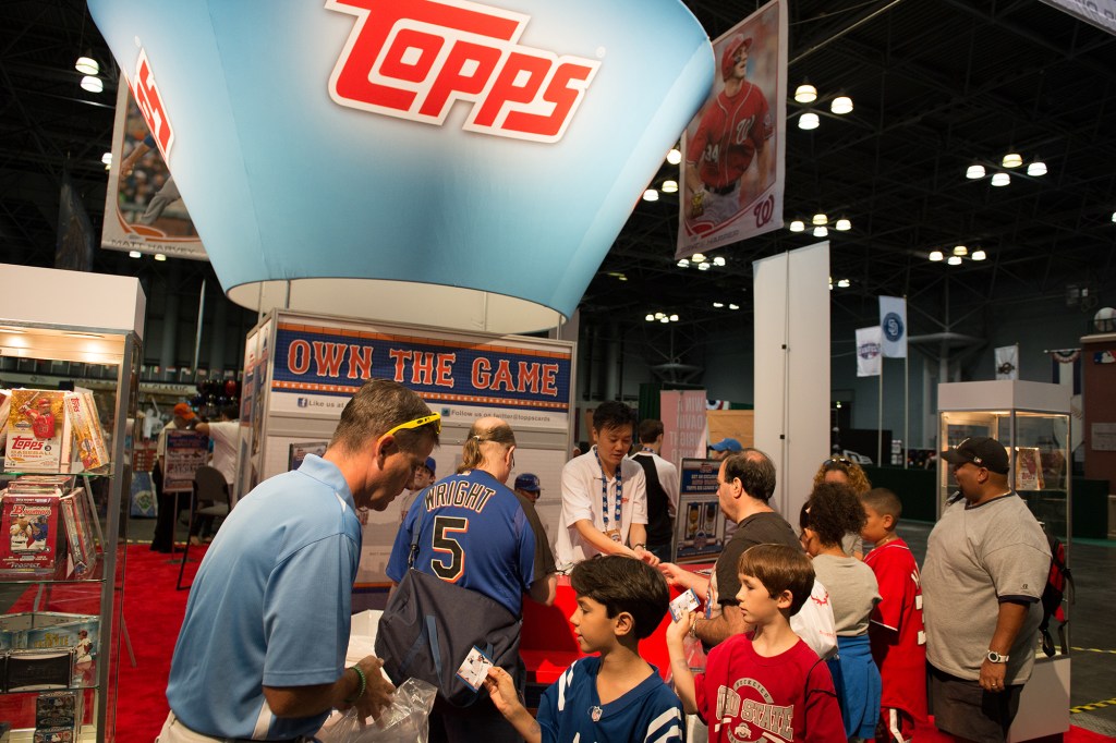 Attendees open packs of trading cards at the Topps booth during the Opening Day of T-Mobile All-Star FanFest at the Jacob K. Javits Convention Center on Friday, July 12, 2013, in New York City.