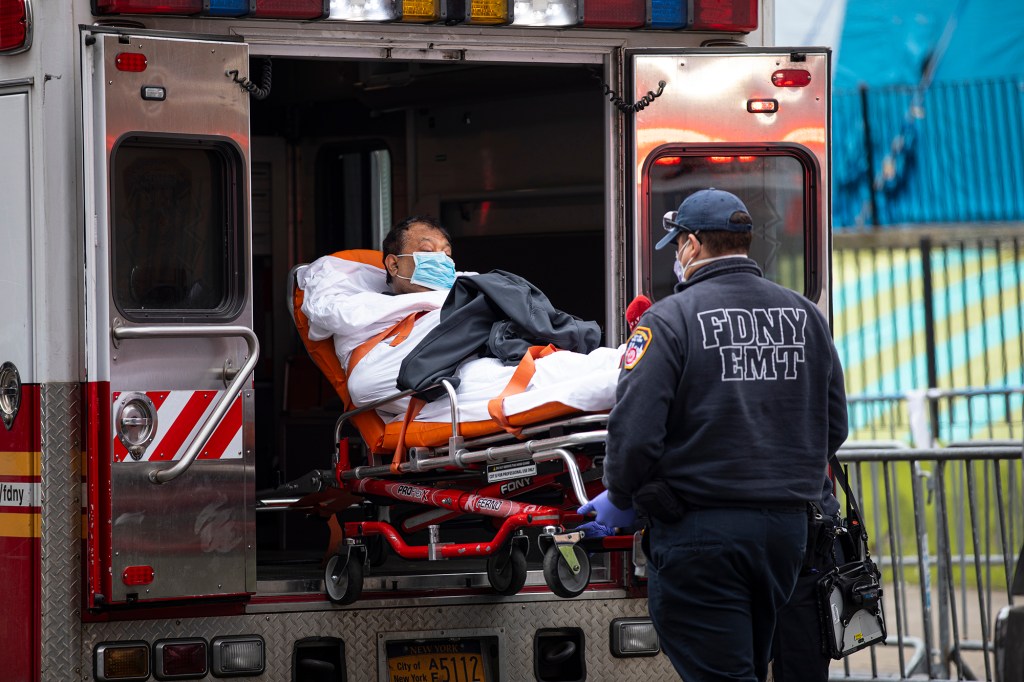 Two members of the Fire Department wheel a COVID-19 patient into an ambulance in NYC.